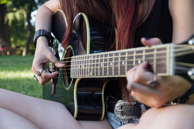 Close-up of woman playing guitar at public park
