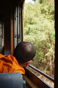 Rear view of mature man looking through window in bus