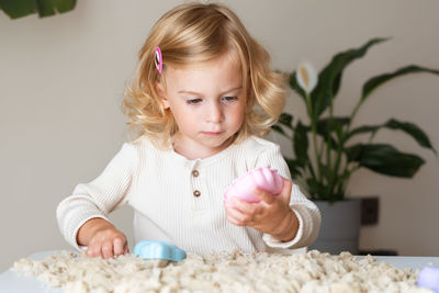 Portrait of cute girl playing with sand and toys at home