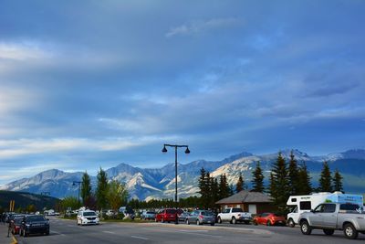 Cars on road against cloudy sky