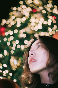 Portrait of woman looking at illuminated christmas tree