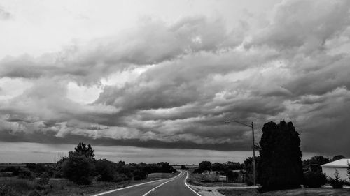 Road by trees against sky in city