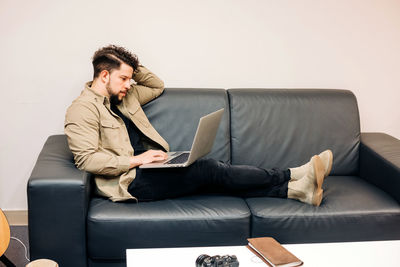 Young man using mobile phone while sitting on sofa