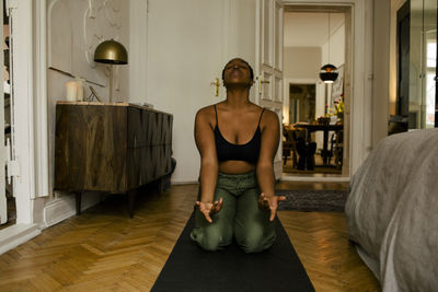 Young woman meditating on exercise mat at home