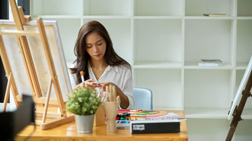 Young woman looking away while sitting on table at home