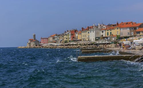 Sea by houses against clear blue sky