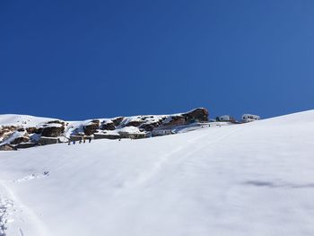 Snow covered landscape against clear blue sky