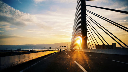 Road by bridge against sky during sunset