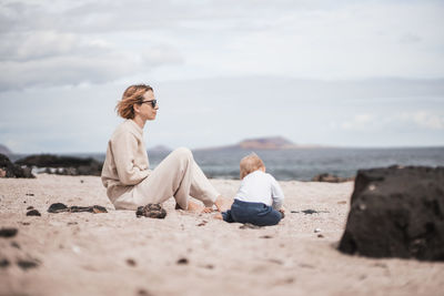 Side view of woman sitting at beach