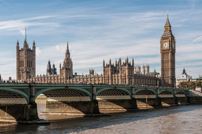 Arch bridge over river and buildings against sky in city