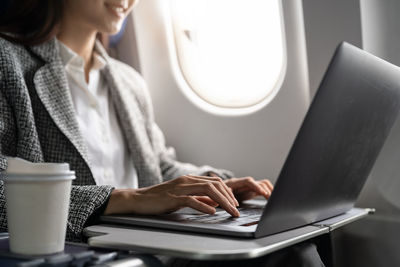 Midsection of woman using laptop at table