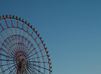 Low angle view of ferris wheel against clear blue sky