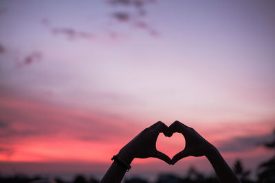 Silhouette hands making heart shape against sky during sunset