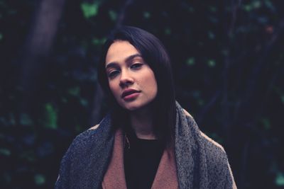 Portrait of woman standing by tree in forest