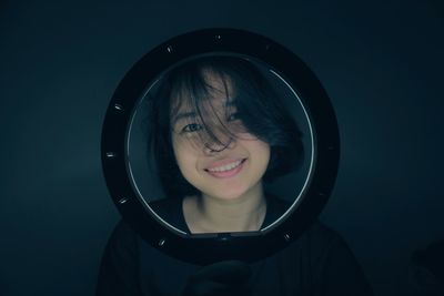 Portrait of young woman looking away against black background