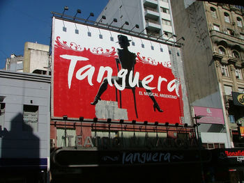 Low angle view of information sign on street against buildings in city