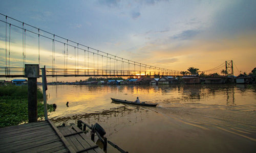 Bridge over river against sky during sunset