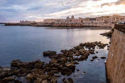 Scenic view of sea by buildings against sky