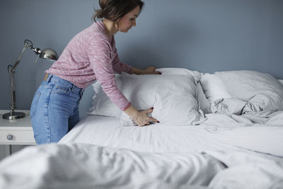 Rear view of woman relaxing on bed at home