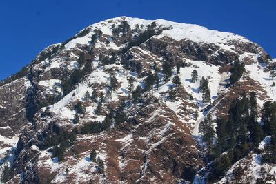 Low angle view of snowcapped mountain against blue sky