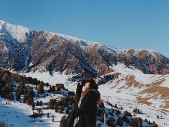 Woman standing against snowcapped mountain