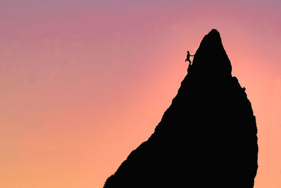 Silhouette person on rock against sky during sunset