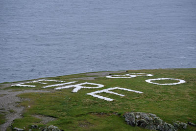 High angle view of text on grass by sea