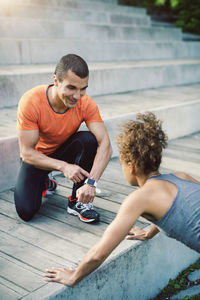 Man showing smart watch to female friend doing push ups