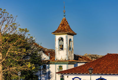 Baroque church bell tower with rising through the trees and roofs of the historic town of diamantina