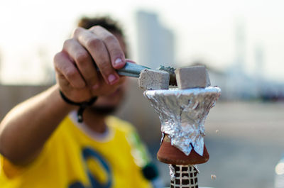 Man placing charcoal burns over hookah