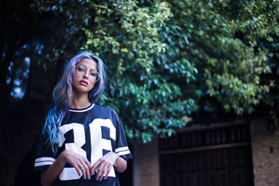 Portrait of emo young woman standing against tree