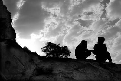 Low angle view of silhouette man sitting against sky