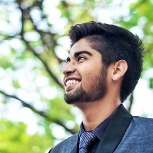 Close-up of smiling man looking away against tree