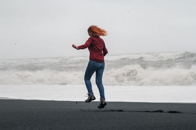 Funny tourist jumping on black iceland beach scenic photography
