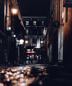 Empty alley amidst buildings in city at night