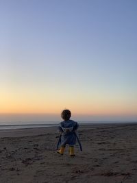 Full length of man on beach against sky during sunset