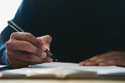 Midsection of man reading book on table