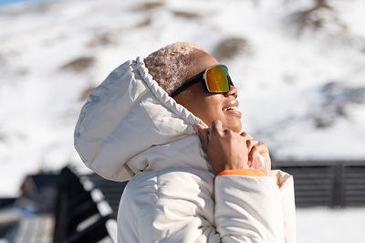 A young african american woman wearing sunglasses having fun in the snow on a winter day