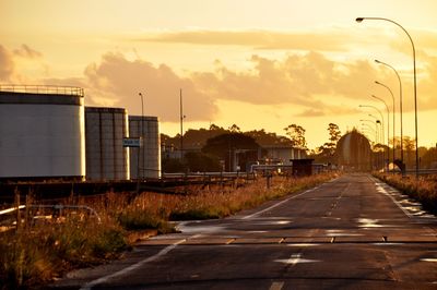 Road by city against sky during sunset