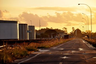 Road by city against sky during sunset