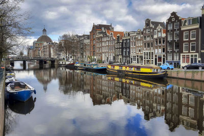 Boats moored on canal amidst buildings in city