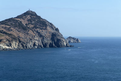 Scenic view of sea and mountains against clear blue sky