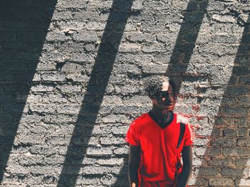 Thoughtful young man standing against wall