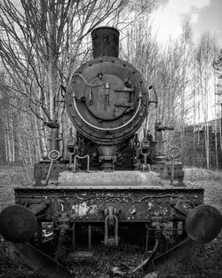 Old railroad track amidst trees against sky