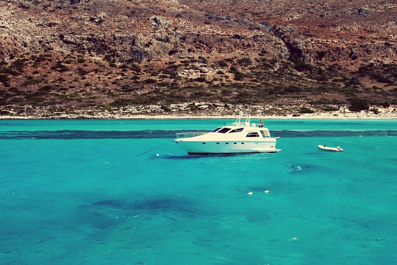 water, nautical vessel, transportation, boat, mode of transport, blue, sea, tranquility, high angle view, tranquil scene, nature, beauty in nature, scenics, waterfront, moored, day, travel, turquoise colored, tree, outdoors