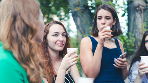 Portrait of a young woman drinking from smart phone