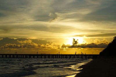 Beautiful twilight golden color and silhouette old bridge with clouds landscape waves sea background