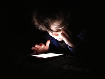 Close-up of boy using digital tablet in darkroom