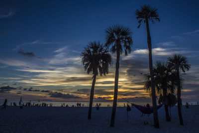 Silhouette palm trees on beach against sky at sunset
