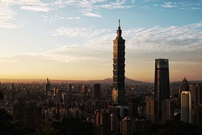 Modern buildings in city against sky during sunset